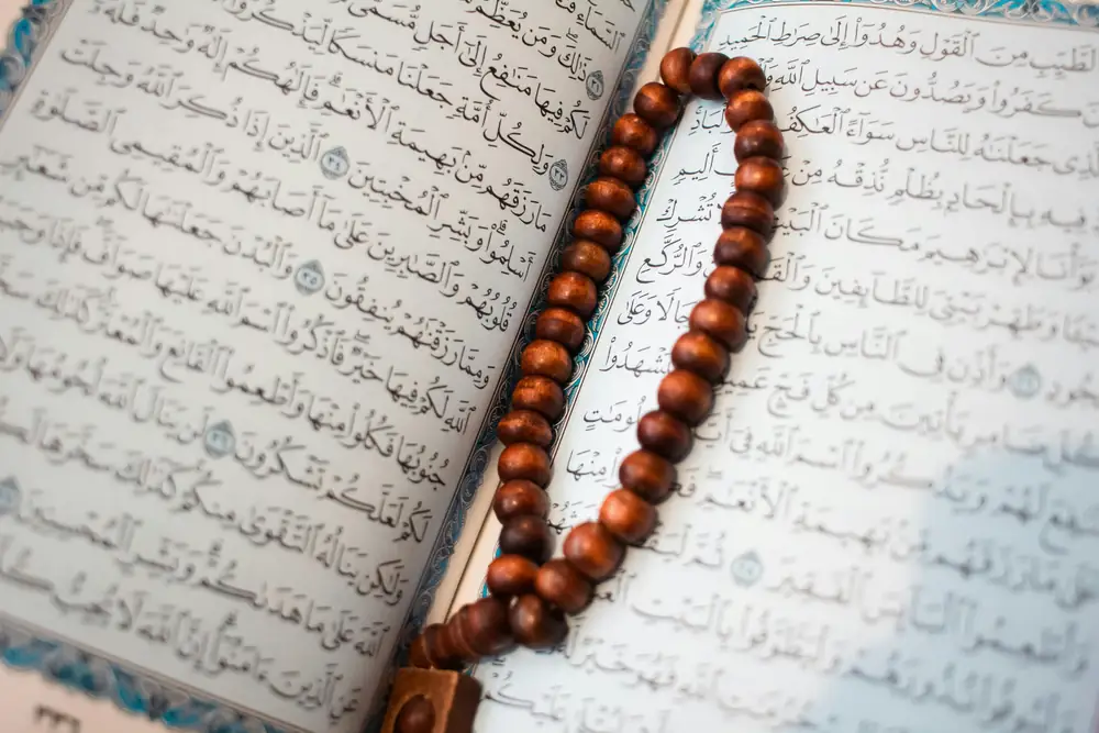 An open Quran with prayer beads