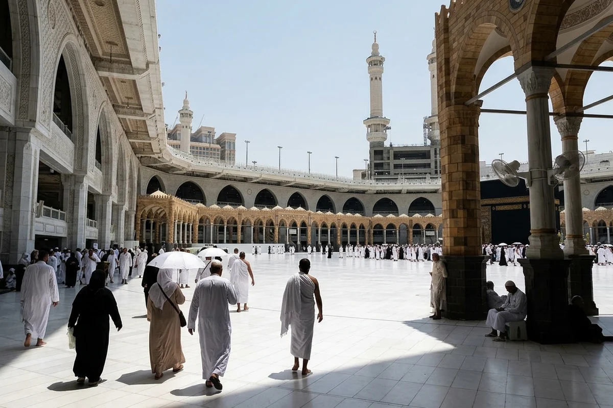 Pilgrims walking out from a shaded arcade into a sunlit mosque courtyard