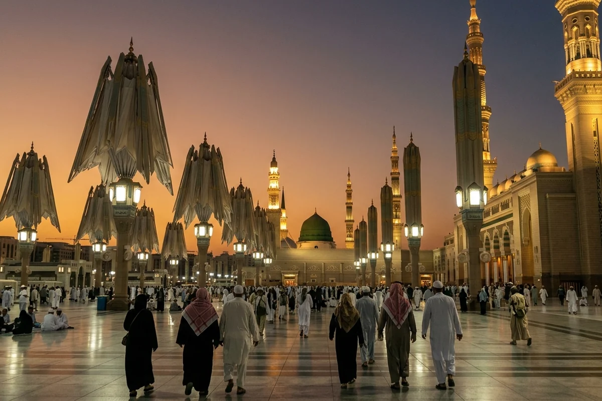 The folded courtyard umbrellas and Green Dome of Masjid an-Nabawi at sunset, with worshippers walking below