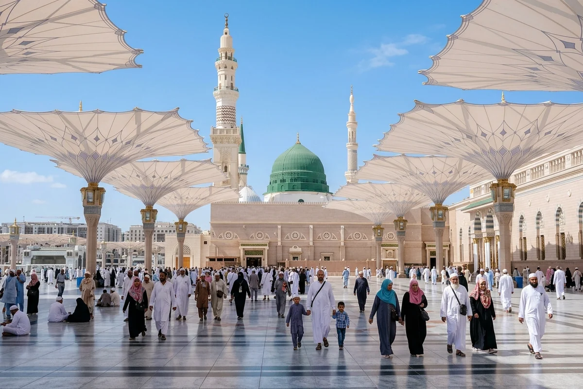 The Green Dome of Masjid an-Nabawi seen between the open courtyard umbrellas, with worshippers walking below