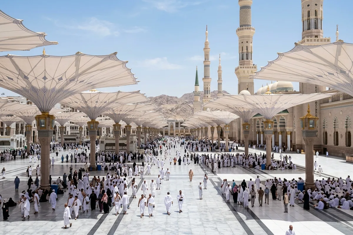 The open courtyard umbrellas of Masjid an-Nabawi in bright sunlight, with worshippers walking beneath them