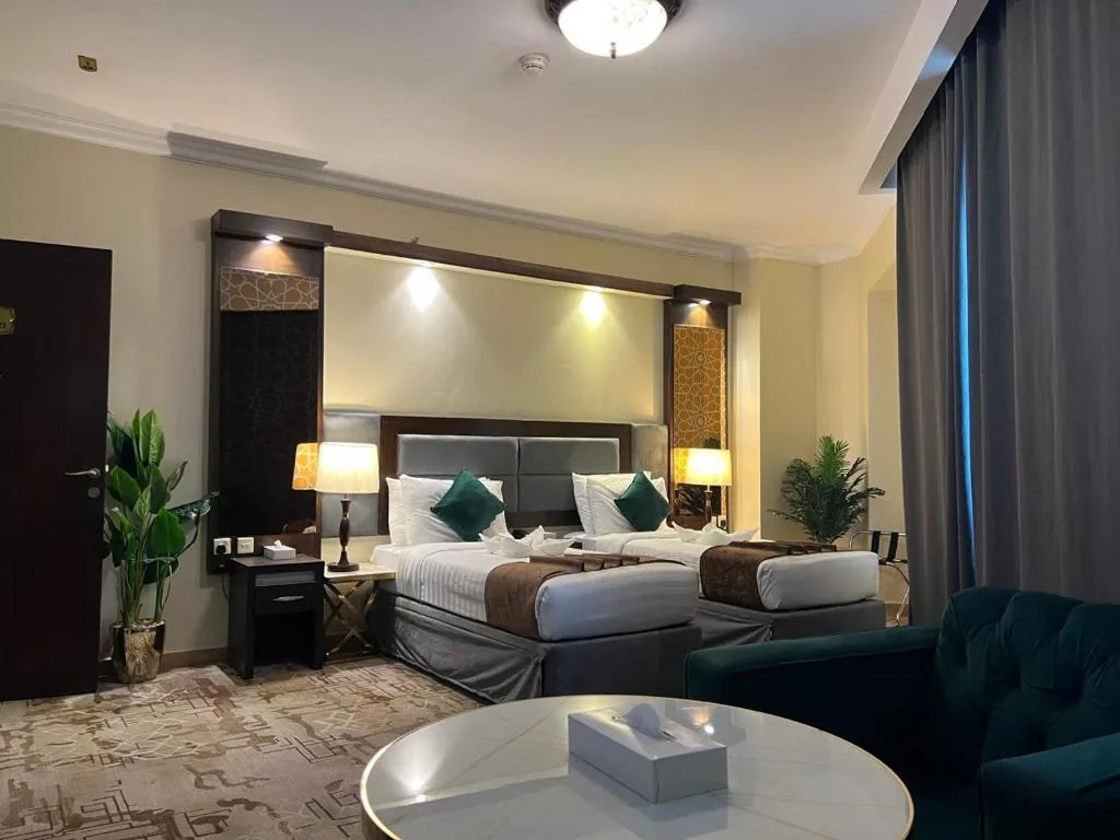 A room with two beds, an armchair and a round table at Sky View Hotel