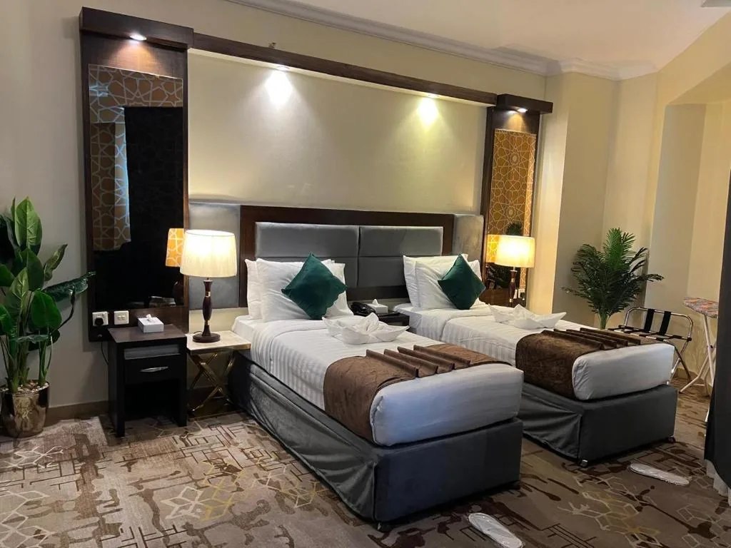 A room with two single beds, bedside lamps and a patterned carpet at Sky View Hotel